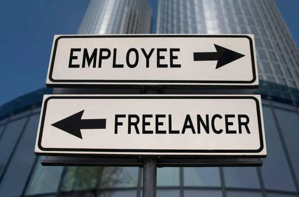 Employee versus freelancer road sign with two arrows on business skyscraper background.
